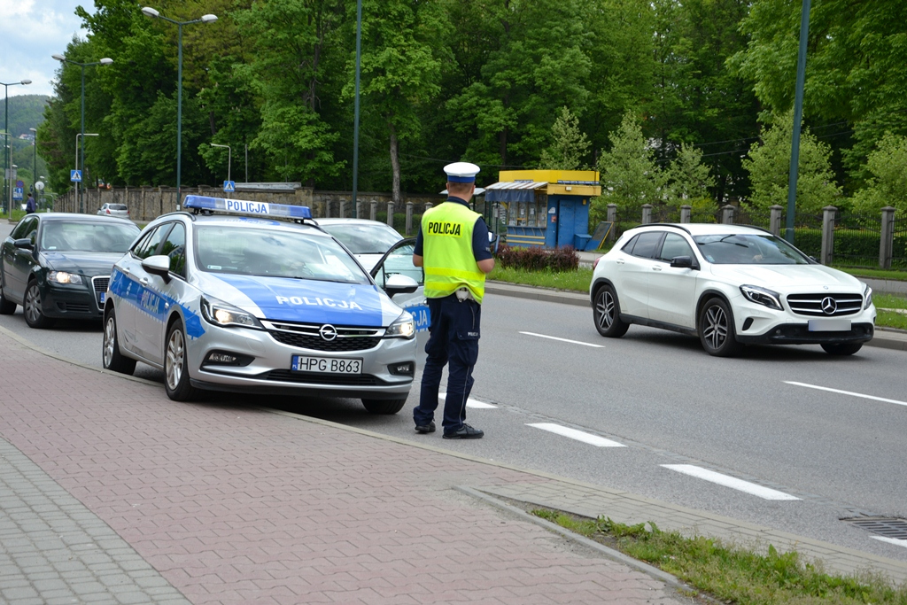 policjant ruchu drogowego obok radiowoz i przejezdzajace samochody