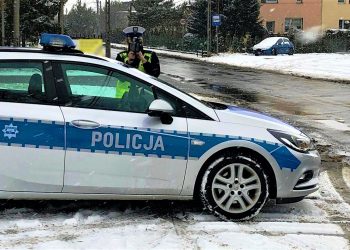 policjantka przy radiowozie z laserowym miernikiem predkosci zima padajacy snieg