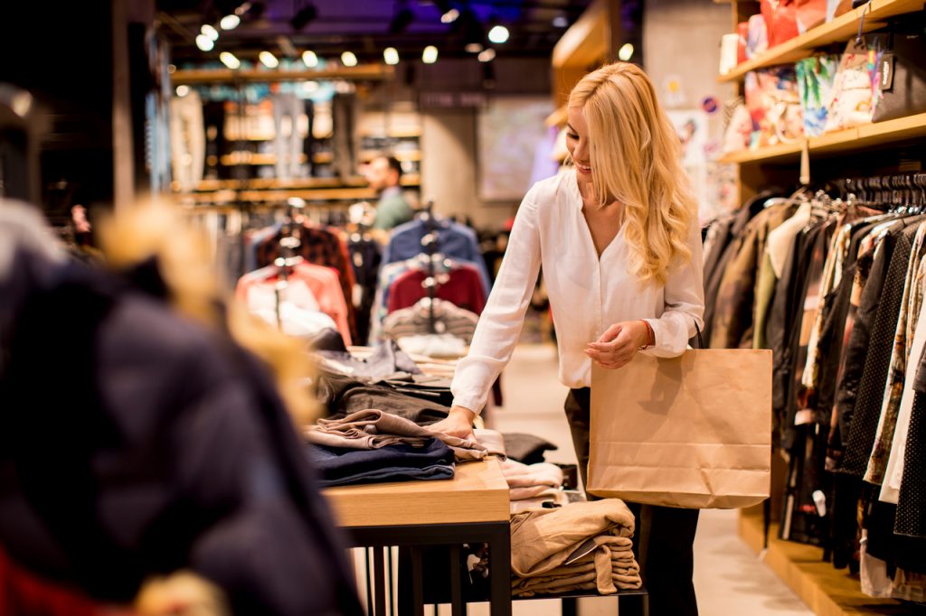 young woman with shopping bags standing clothing store