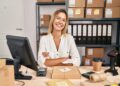 Young blonde woman working at small business ecommerce happy face smiling with crossed arms looking at the camera. positive person.