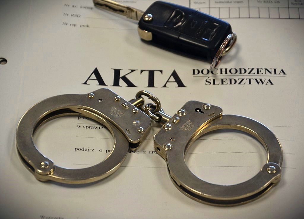 policjakajdanki oraz kluczyk do samochodu polozone na okladce akt