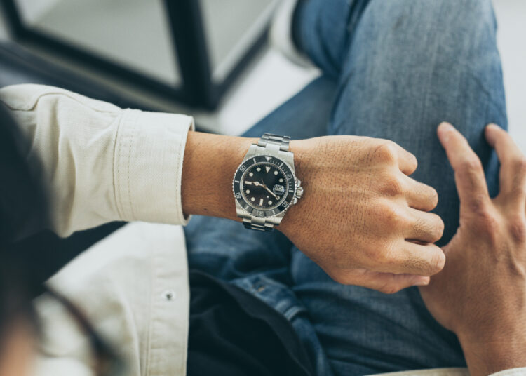 fashionable wearing stylish looking at luxury watch on hand check the time at workplace.concept for managing time organization working,punctuality,appointment