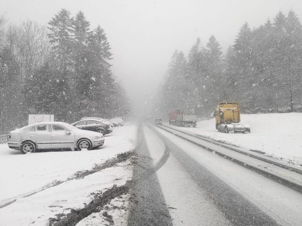 zasniezona droga zimowe warunki zasniezone samochody stoja na poboczu i parkingu