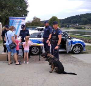 policjapolicjant z psem sluzbowym obok policyjny radiowoz i stoisko profilaktyczne Policji 1