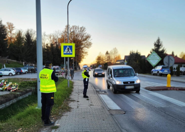 policjantka wspolnie z straznikiem miejskim dbaja o bezpieczenstwo w poblizu przejscia dla pieszych i cmentarza