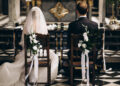 Bride and groom sitting on chairs on their wedding day, from the back