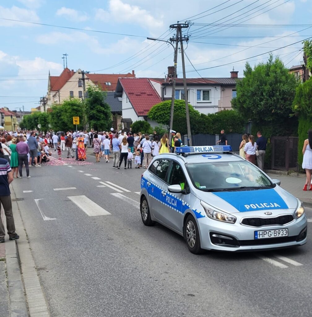 policyjny radiowoz i uczestnicy procesji