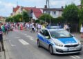 policyjny radiowoz i uczestnicy procesji