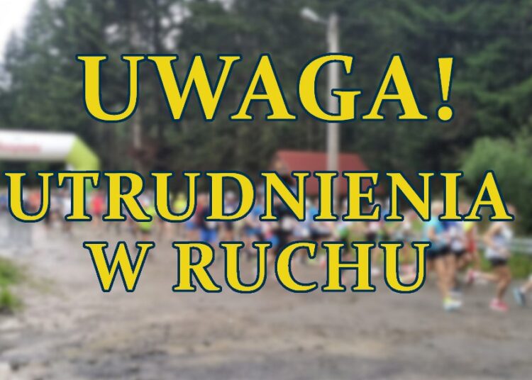 napis UWAGA UTRUDNIENIA W RUCHU w tle rozmyte zdjecie biegaczy