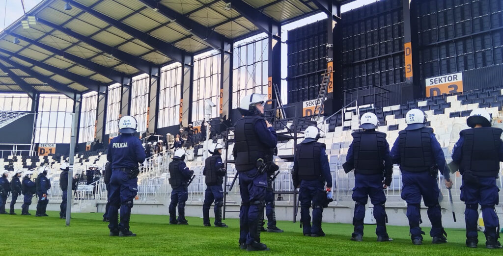 policjanci stoja przed sektorami inni wchodza na murawe